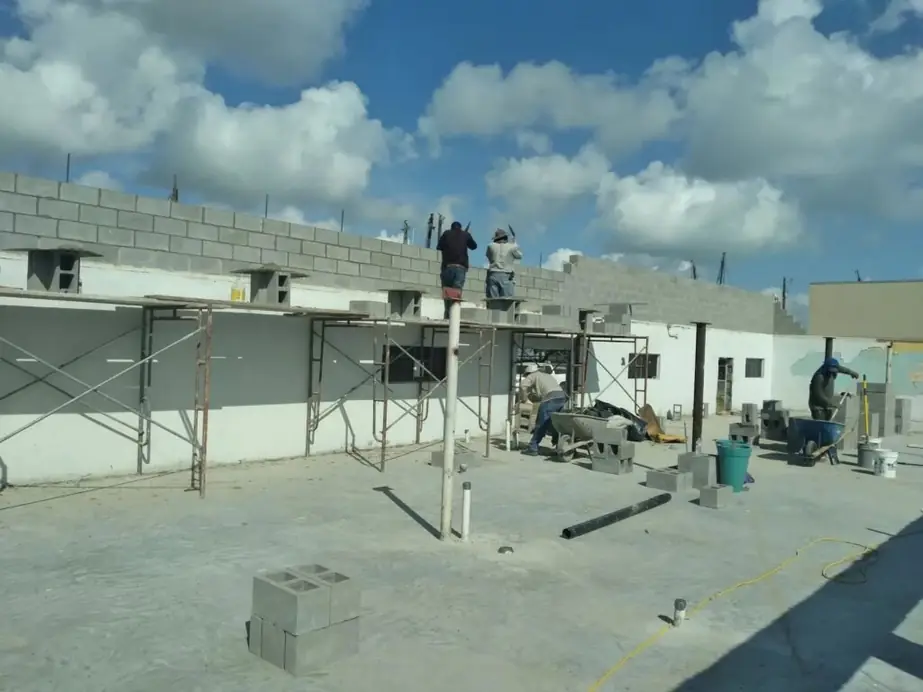 Crew laying block courses from scaffolding