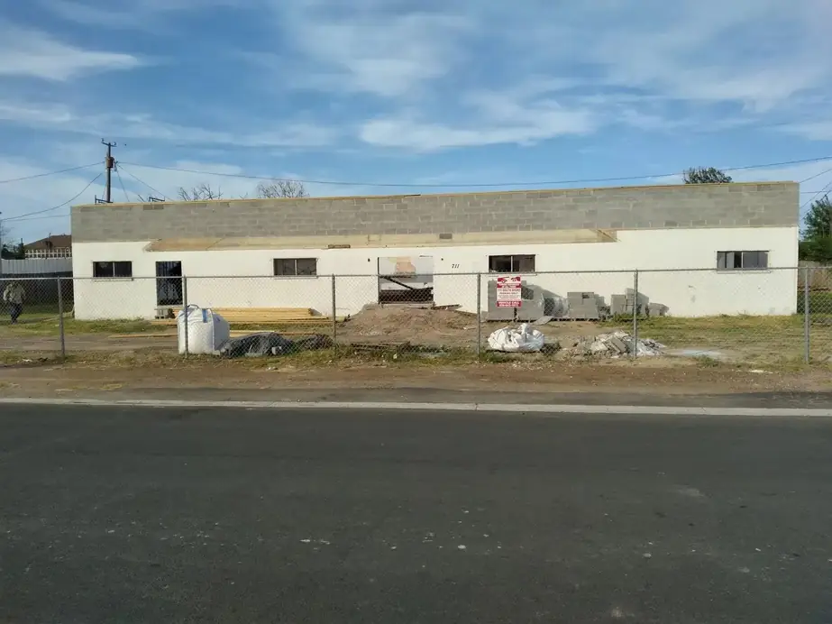 Concrete block building behind chain-link before work began