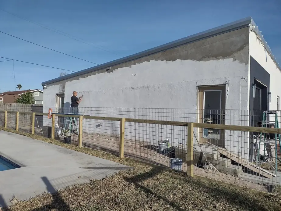 Painter on a ladder finishing the stucco wall