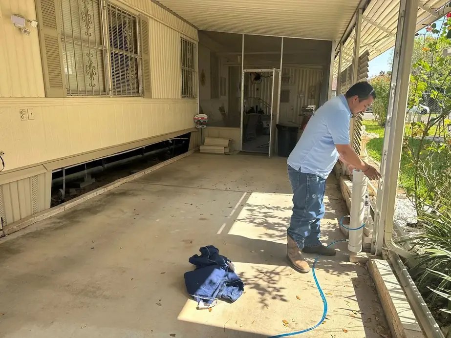 Ariston crew member at the skirting of a manufactured home, the underbelly opened behind him